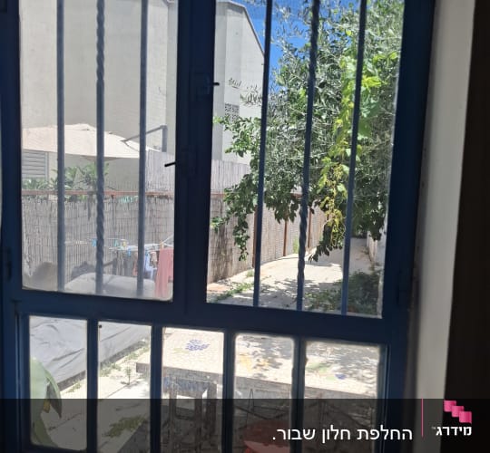 חלון עם סורגים ונוף חצר בחוץ
